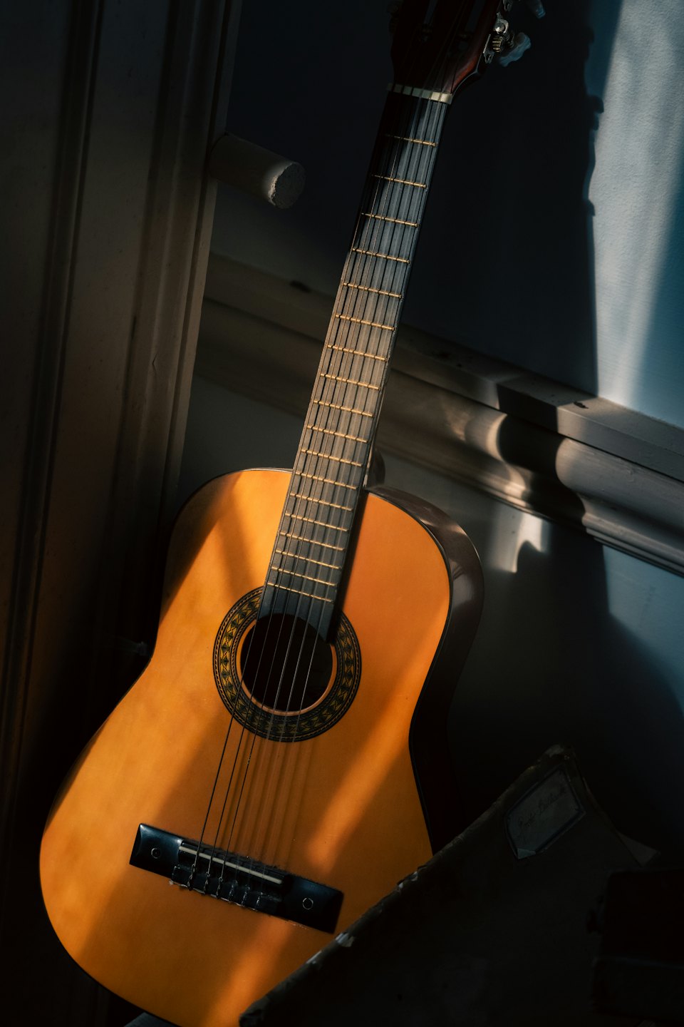 An acoustic guitar leans against a wall beside an old notebook.
