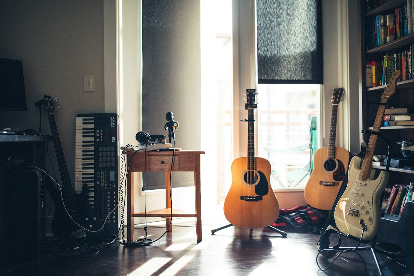 Guitars, keyboard, and microphone in a sunlit home studio.