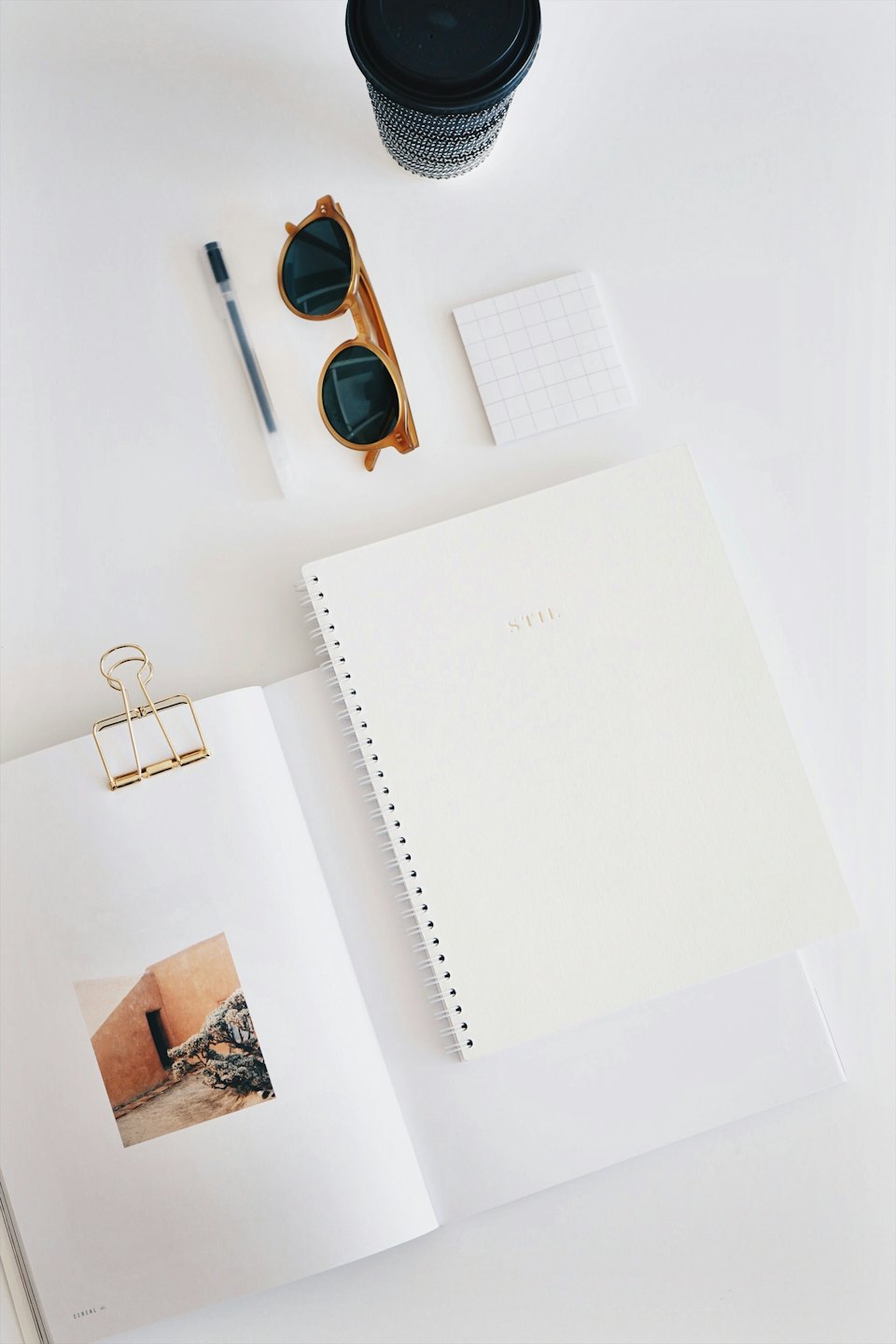 Flat lay of organized desk items with an open magazine.